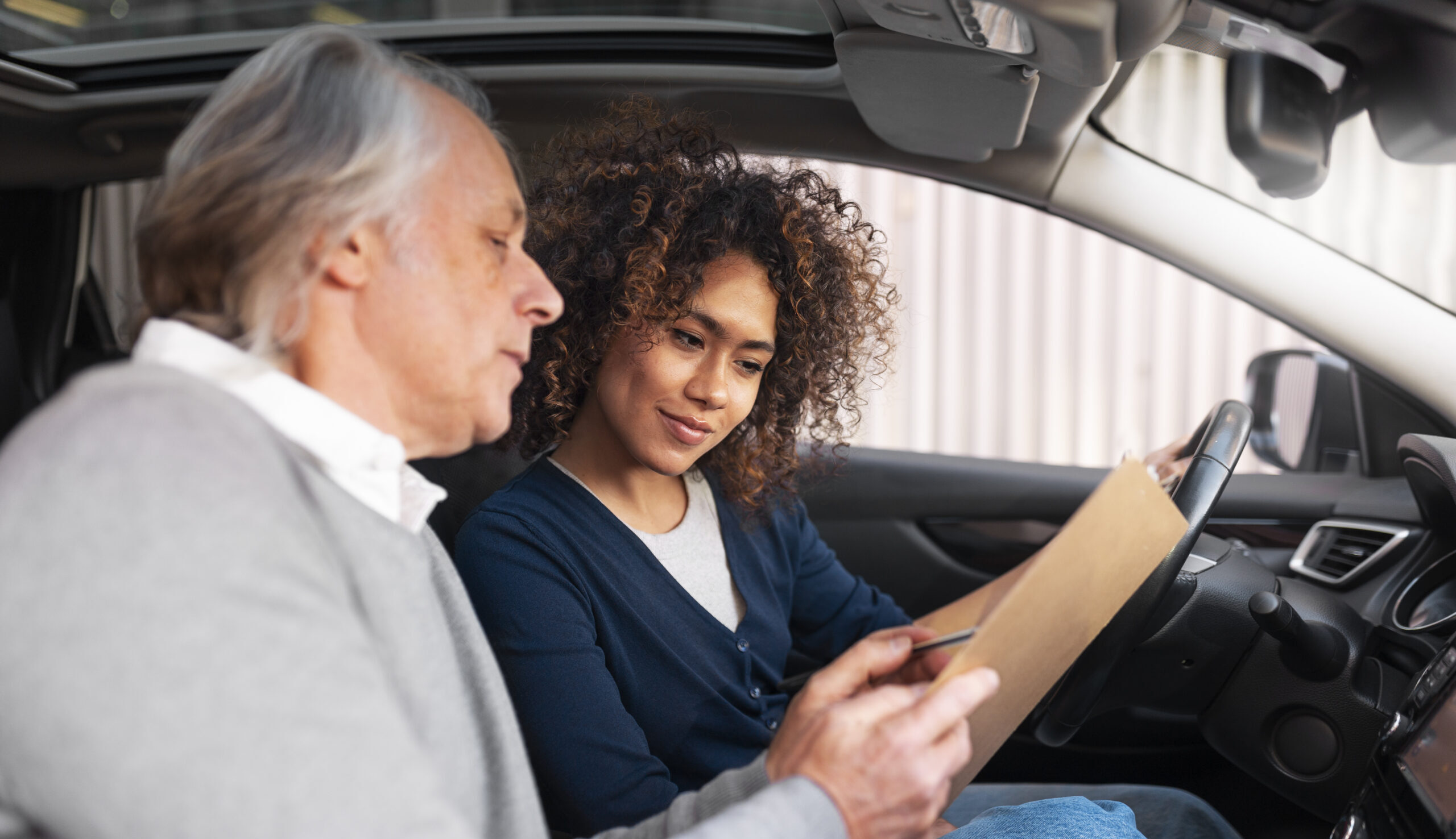 Moniteur d'auto-école qui explique quelque chose à son élève dans la voiture